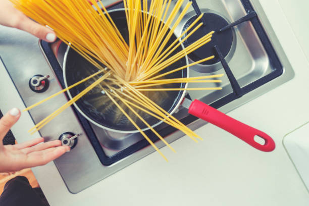 istock Woman dropping pasta into boiling water. 1255815511