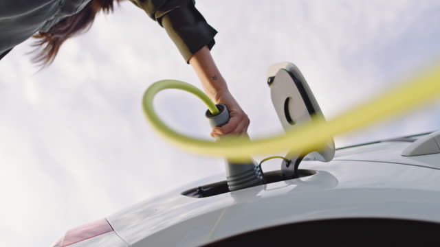 SLO MO Unrecognizable woman inserting an EV plug into a vehicle inlet
