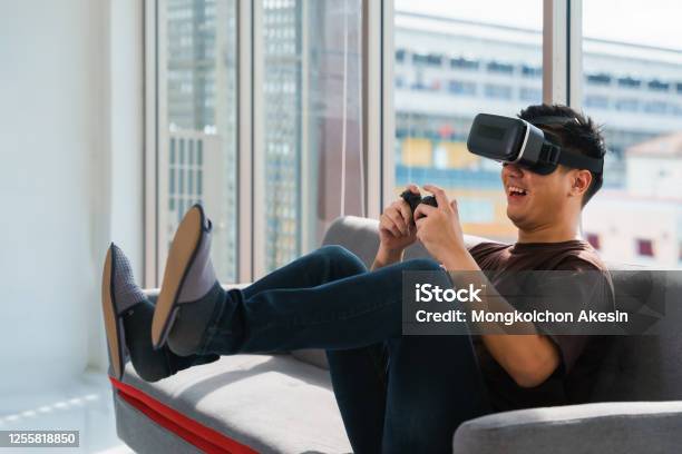 Young Asian Man On Bed Holding Game Joystick And Wear Game 3d Google Glasses Have Fun Playing Video And Console Game At Home Stock Photo - Download Image Now