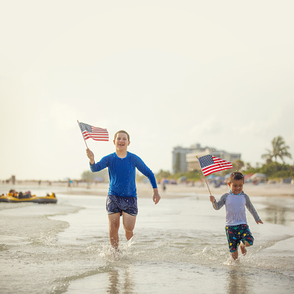 Cuban kids running on the beach holding USA flags