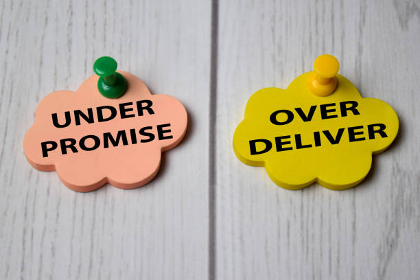 istock Under Promise or Over Deliver write on sticky notes isolated on Office Desk 1255828681