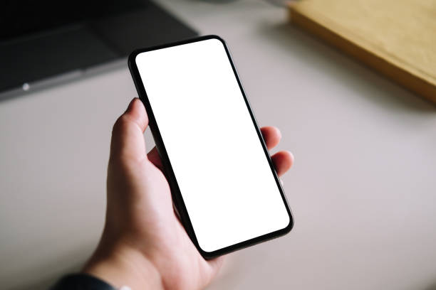 istock Woman using smart phone with blank screen mock up on workplace desk. 1255828712