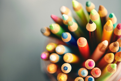 Collection of colored pencils in patriotic American flag jar on worn chalkboard background. Back to school concept.