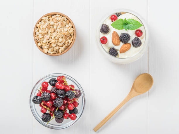 istock Fresh berries, granola, and a glass of yogurt on a white table. 1255831190