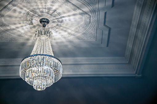 Chandelier with lamps. Light in interior. Antique glass chandelier. Ceiling in hall.