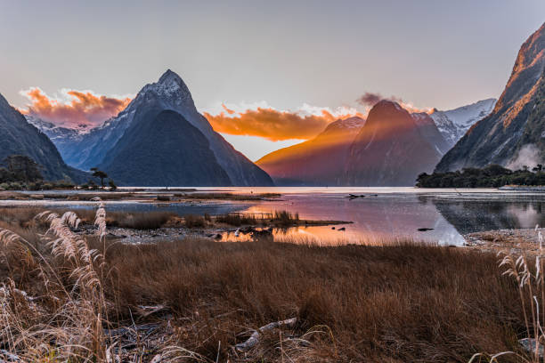 Mitre Peak Sunset-Milford Sound New Zealand view of Milford sound at low tide -sunset with mountains and mitre peak reflected in glowing sky milford sound stock pictures, royalty-free photos & images