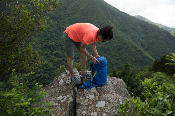 istock Successful woman hiker packing the backpack hiking on cliff edge 1255840918