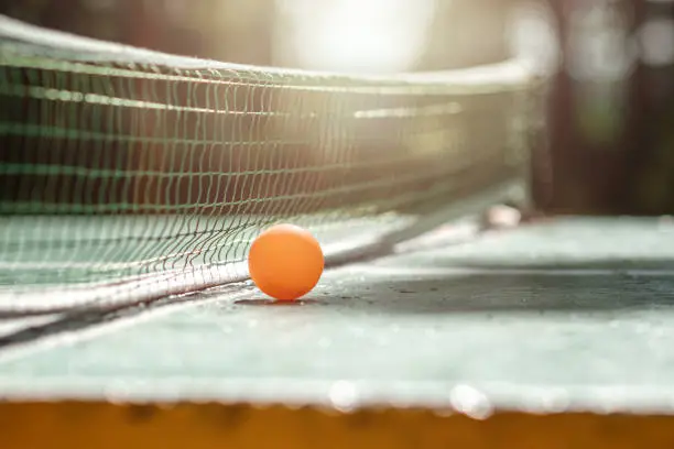The concept of sports games, healthy lifestyle. Orange ball on a grid background on a ping pong table. Copy space, soft focus