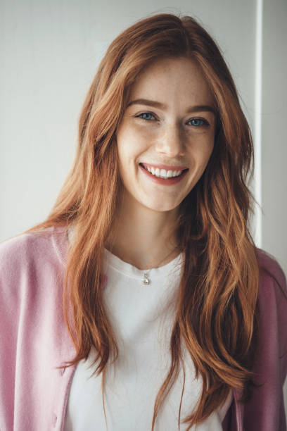 istock Ginger lady with freckles smiling toothily at camera wearing a white tshirt and pink pullover 1255845243
