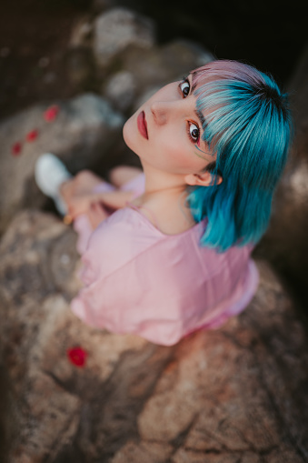 Portrait of teenage girl with blue and pink dyed hair wearing pink dress