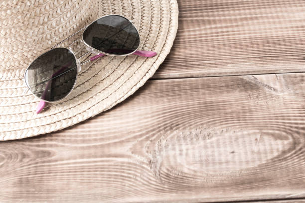 istock Sunglasses on a straw hat on a wooden table. 1255848416