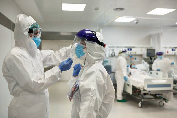 istock Hospital Coworkers Helping Each Other with Face Protection 1255849312