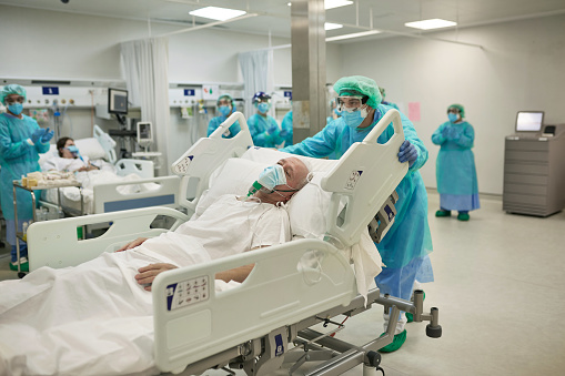 Trabajador de la salud que se muda a UN PACIENTE COVID-19 en la cama del hospital photo
