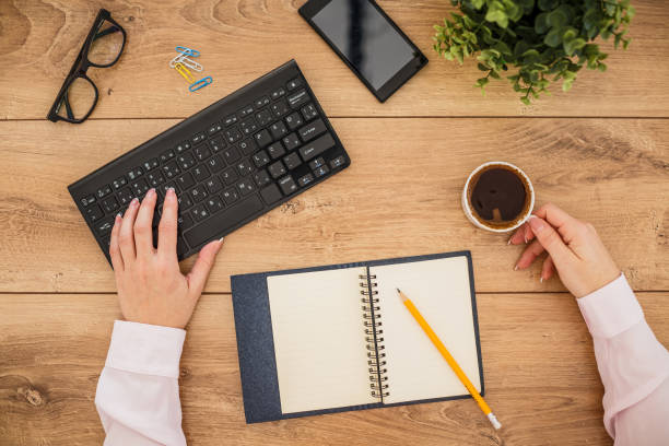 istock Female hands holding a cup of coffee and typing on a computer keyboard 1255850686