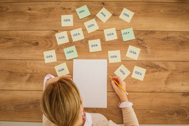 istock Woman thinking about ideas to write down on a piece of paper 1255850729