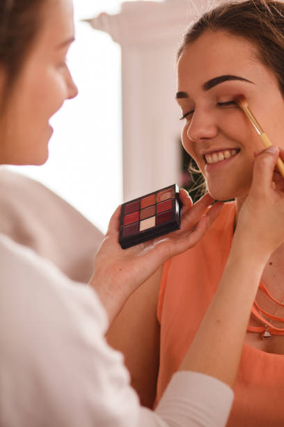 istock Make up artist holding eyeshadow pallet and applying it on a smiling client 1255850844