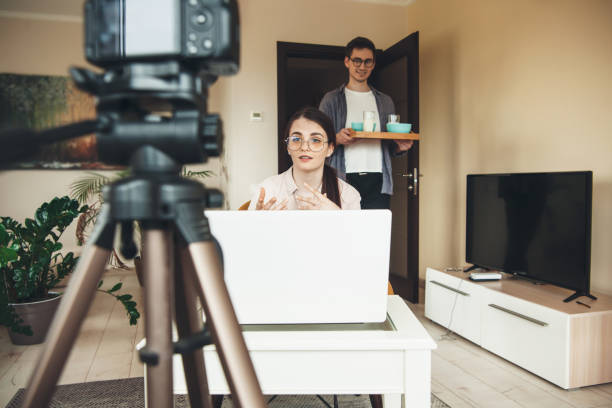 istock Cute caucasian woman having online lessons is explaining something while her lover is brinking the breakfast 1255852486