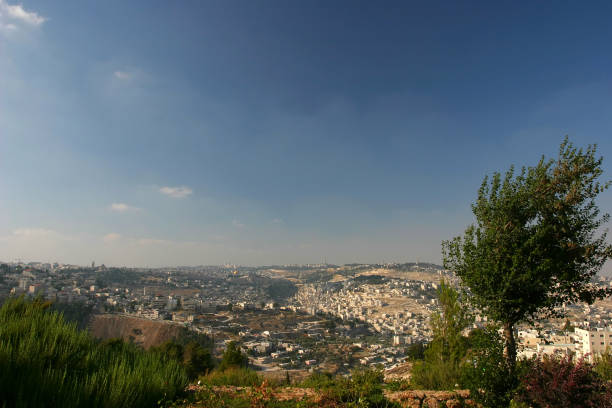 The street and old stone wall going down to Mount of Olives from Jerusalem Old Town in Israel, with the cars parked along the way.