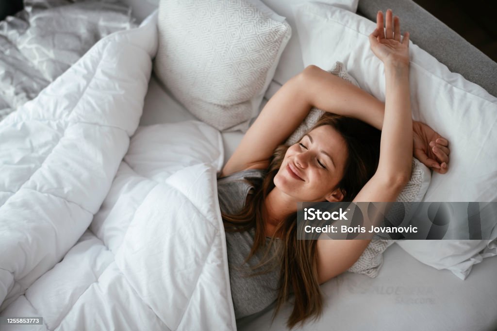 Mujer estirada en la cama después de despertar. - Foto de stock de Dormir libre de derechos