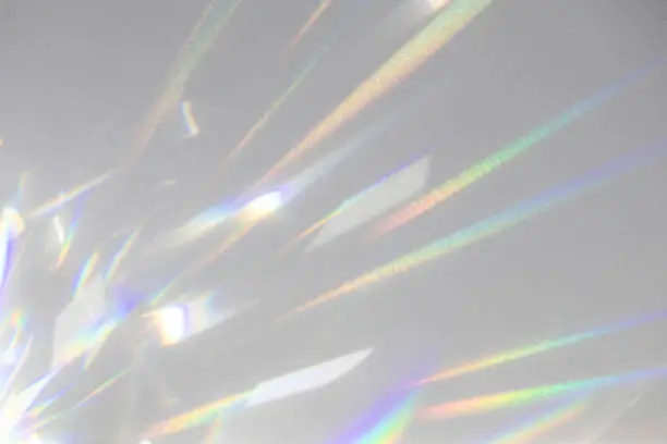 Blurred rainbow light refraction texture overlay effect for photo and mockups. Organic drop diagonal holographic flare on a white wall. Shadows for natural light effects