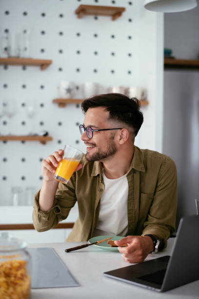 istock Young man eating breakfast and reading the news online. 1255854012