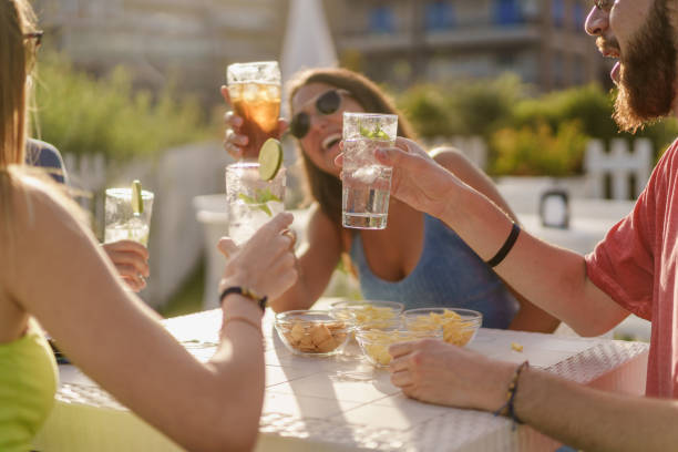 happy hour brindis. jóvenes amigos clinking con mojitos frescos sentados en un mostrador restaurante y tomando un aperitivo en el verano. concepto de amistad y unión - tequila reposado fotografías e imágenes de stock