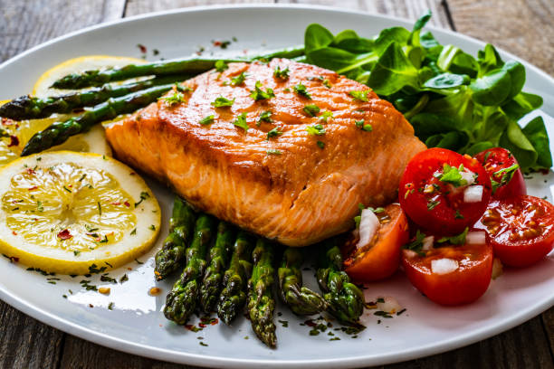 istock Fried salmon steak and asparagus on wooden table 1255857114