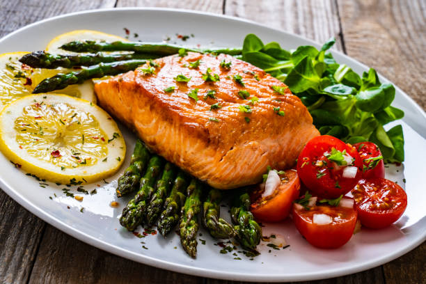 istock Fried salmon steak and asparagus on wooden table 1255857165