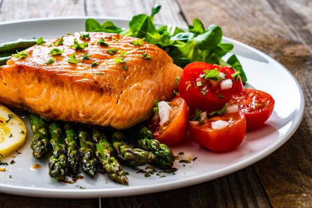 istock Fried salmon steak and asparagus on wooden table 1255857192
