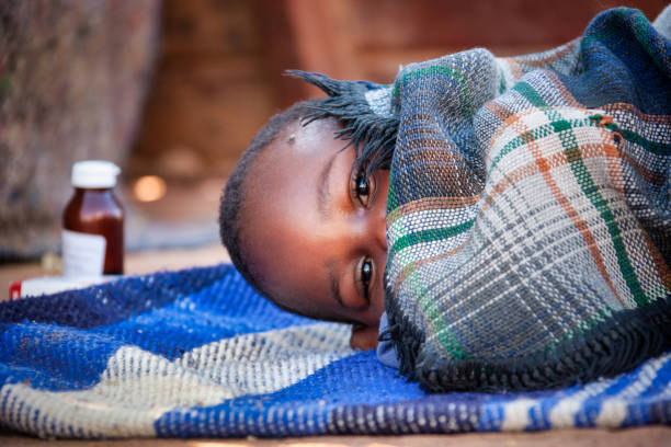 african child toddler sick with malaria african child toddler sick with malaria medicine in the background, laying down on a blanket in the yard malaria stock pictures, royalty-free photos & images