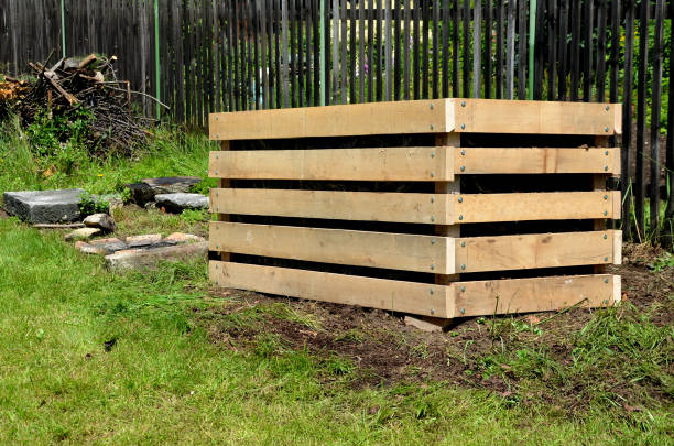 istock A composter made of natural beech prisms built horizontally with black foil inside in a meadow near a dark wooden fence. The composting process of rotting processes grass leaves and food scraps. 1255859150