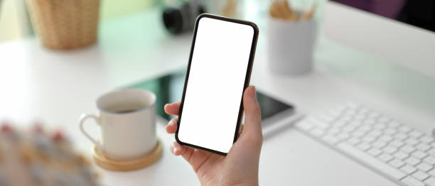 istock Female hand holding mock-up smartphone while standing at office desk 1255860433