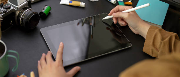 istock Female designer drawing on digital tablet with stylus pen on worktable with painting tools 1255861411