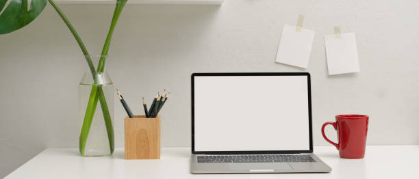 istock Simple workspace with mock-up laptop, mug, pencils and plant vase on white table 1255861479