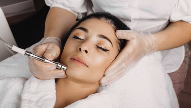 Facial care procedure with apparatus to a brunette woman lying on the spa couch with closed eyes stock photo
