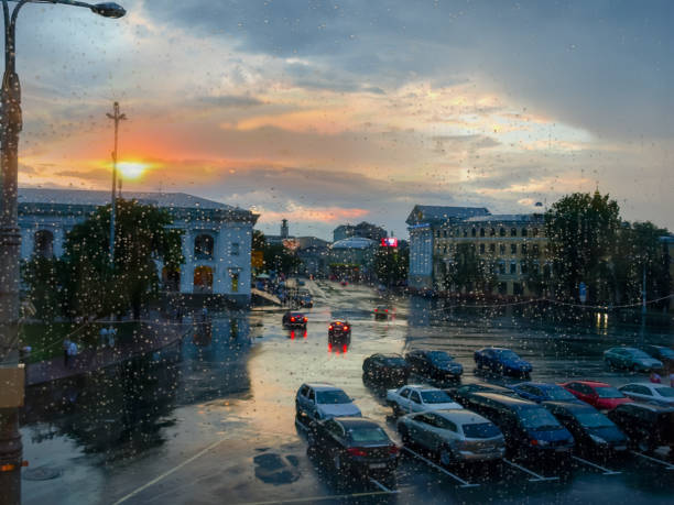 istock Blurred cityscape through the window pane during rain at sunset 1255870148