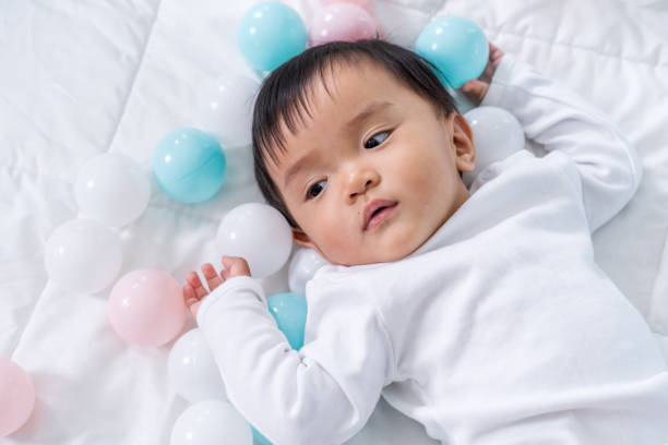 istock cheerful baby playing color ball on bed 1255870530