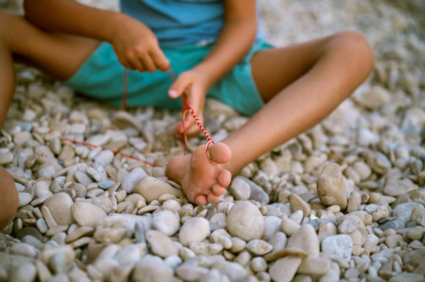istock Toddler boy making a knotted bracelet on the beach 1255870991
