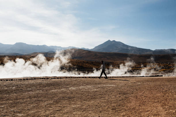 homme dans le champ géothermique d’el tatio de marche dans les montagnes à atacama - geyser nature south america scenics photos et images de collection