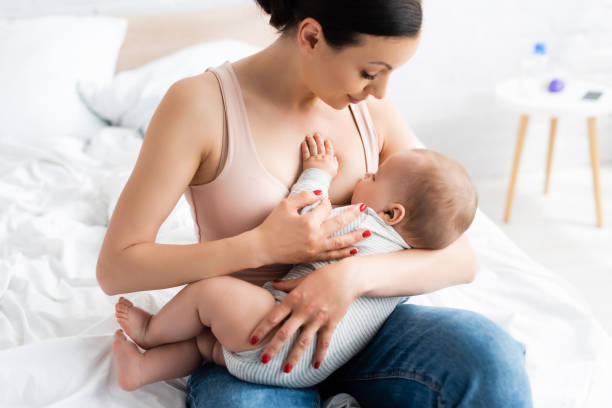 caring mother breastfeeding baby boy in bedroom caring mother breastfeeding baby boy in bedroom breastfeeding photos stock pictures, royalty-free photos & images