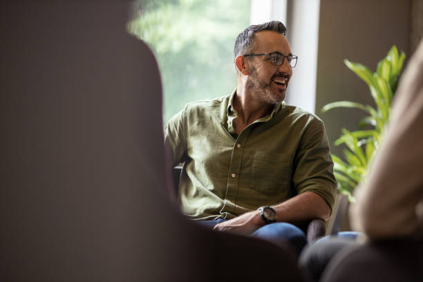 Mature businessman laughing during a meeting with office colleagues Mature businessman laughing during a meeting with colleagues in a modern office real life stock pictures, royalty-free photos & images