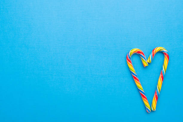 istock Multi-colored candy canes in the form of a heart on a blue background, copy space 1255873754