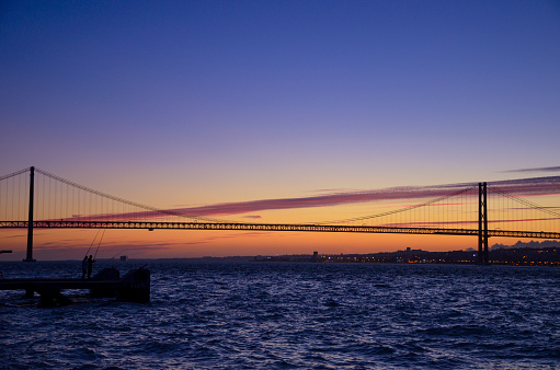The 25th of April suspension bridge over the Tagus river, at sunset, in Lisbon, Portugal.