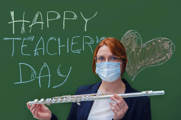 Music teacher in a medical mask with a flute in his hands. Learning problems concept during quarantine coronavirus
