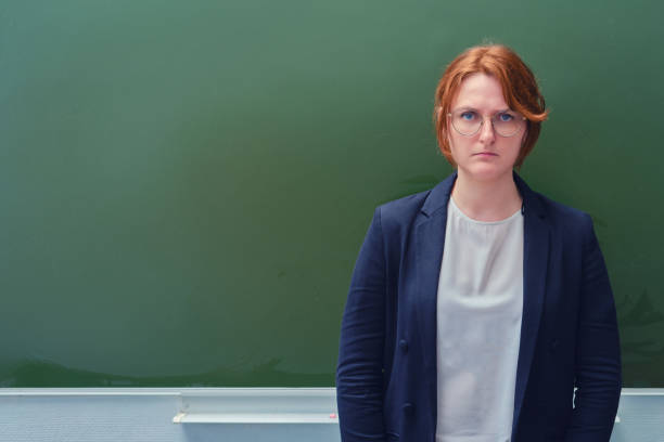 istock An angry schoolteacher stands at the blackboard with a sad face, copy space 1255877792
