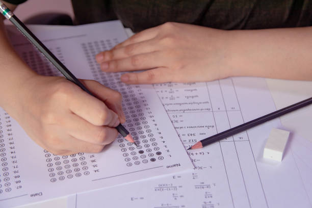 die schülerinnen und schüler halten die hand mit bleistift-schreiben ausgewählte auswahl auf antwortblättern und mathematikfrageblättern. studenten, die die prüfung der prüfung prüfen. schulprüfung - medical exam stock-fotos und bilder