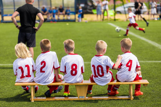 サッカーの試合を見て子供サッカーチーム。白いシャツを着て子供のスポーツチーム。子供のための青少年サッカースクールトーナメント。サッカージャージーのヤングボーイズ。サッカー� - ベンチ ストックフォトと画像