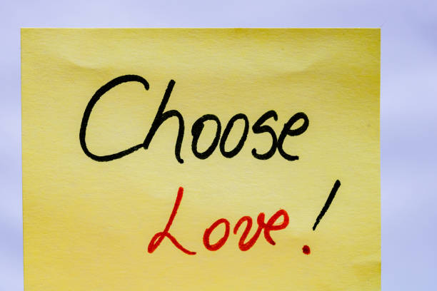 istock Choose love handwriting text close up isolated on yellow paper with copy space. 1255887109