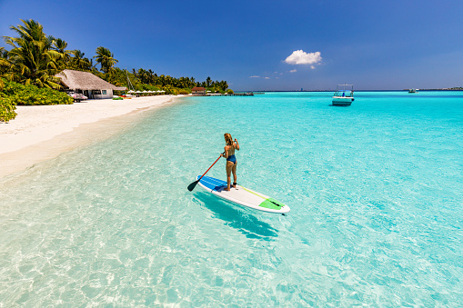 High angle view of a woman from the back on a stand up paddle during summer day at sea. Copy space.