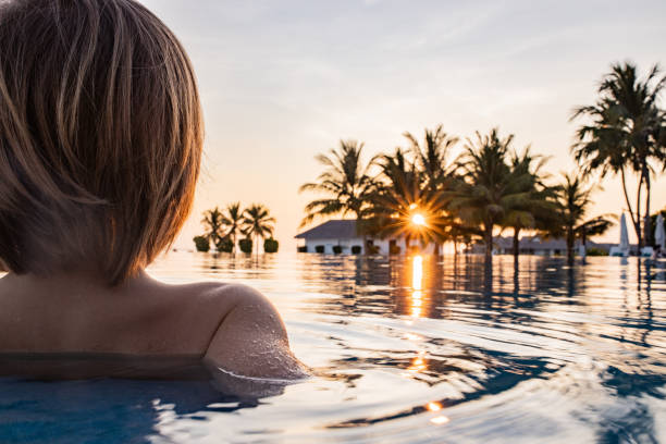 istock Back view of small kid in infinity pool at sunset. 1255889739